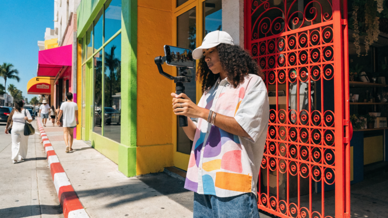 A content creator filming a vertical short-form video of a vibrant South Florida business on a smartphone gimbal