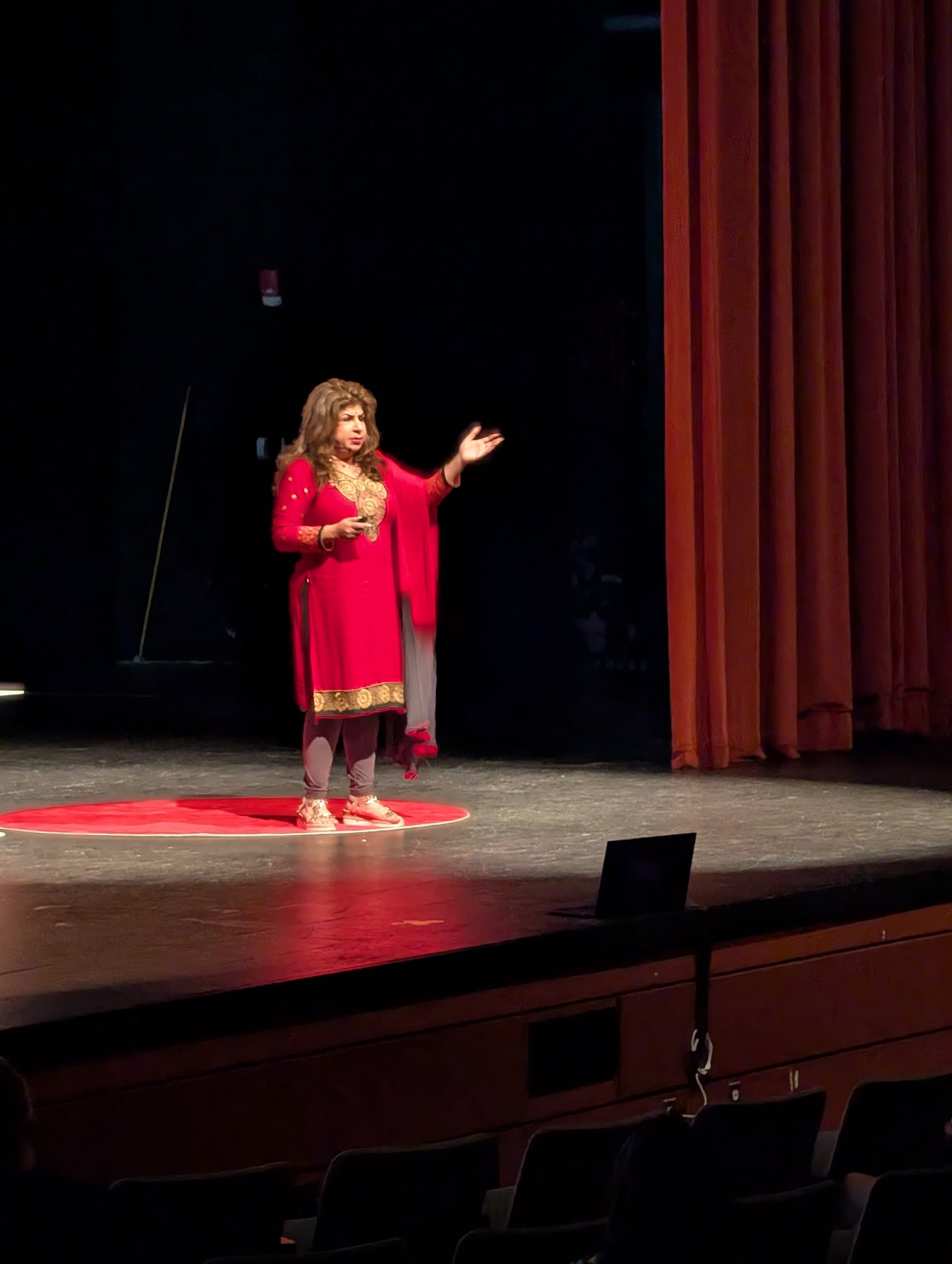 A TEDx Butterfish Cove speaker in red on the red circle during her talk