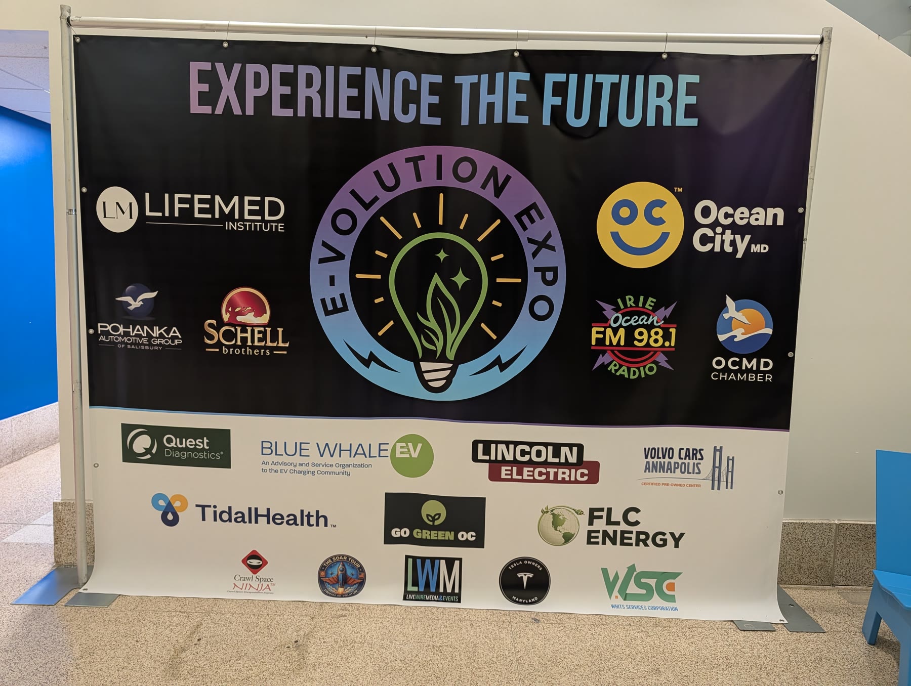 E-Volution Expo Experience the Future sponsor wall with logos of LifeMed Institute, Ocean City MD, Blue Whale EV, Lincoln Electric, TidalHealth and more