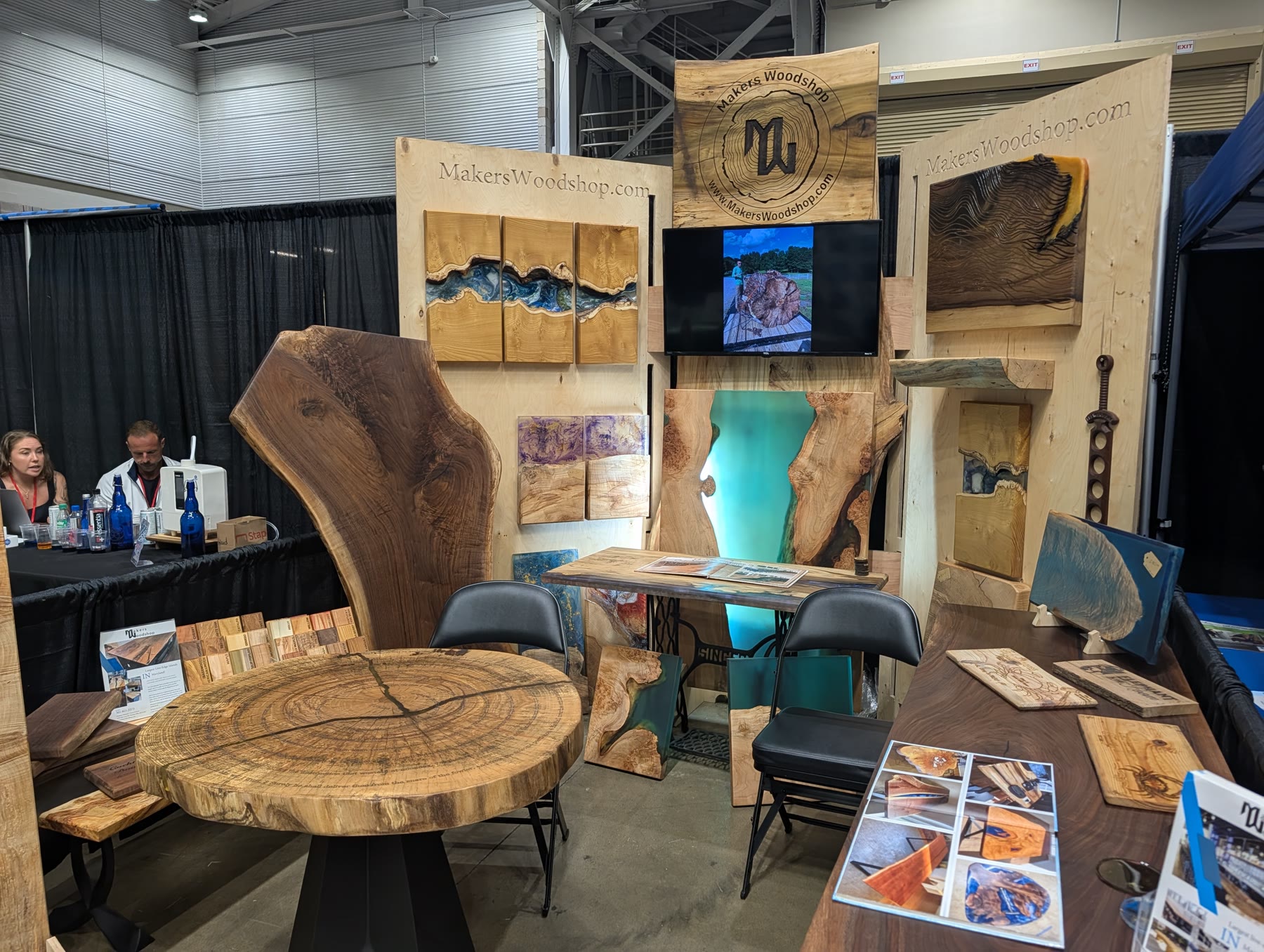 Makers Woodshop booth with live-edge walnut slabs and a glowing resin river table