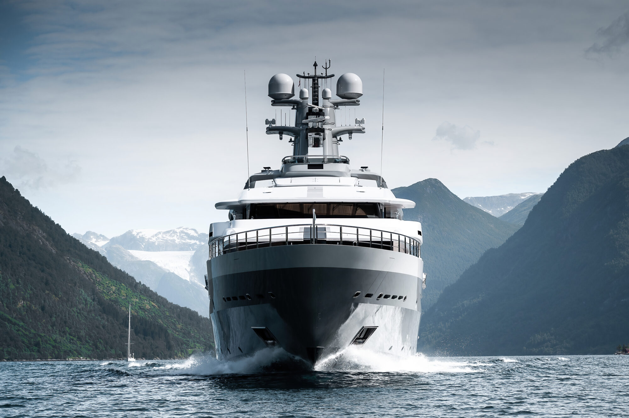 Draak, the grey 92.9-metre Oceanco support yacht, bow-on in a Norwegian fjord with snow-capped mountains behind